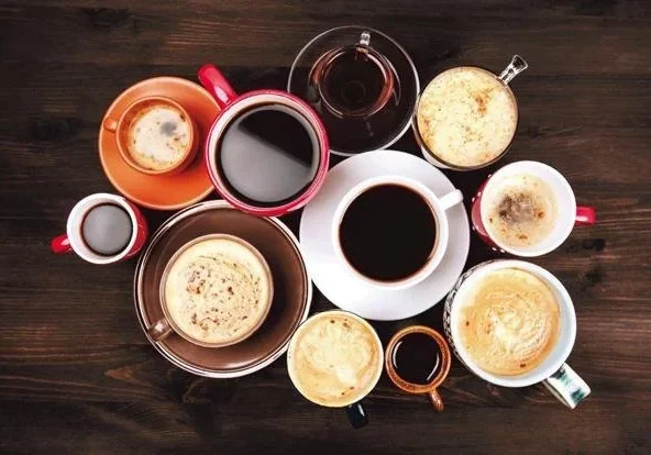 Various coffee cups arranged on wooden table.